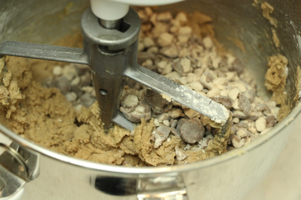 Adding crushed malted milk balls to cookie recipe, using KitchenAid stand mixer.