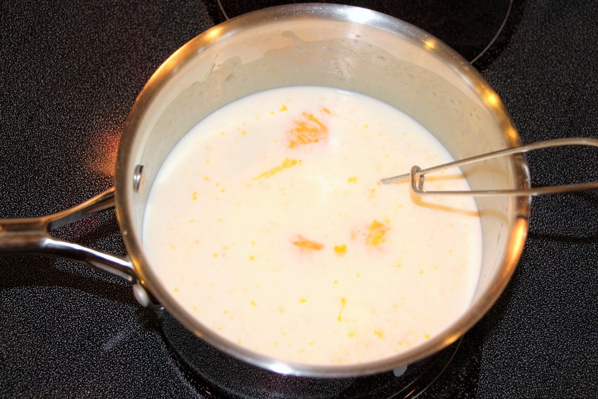 Adding milk and egg yolks in a roux to make white sauce for Norwegian fish and macaroni casserole.