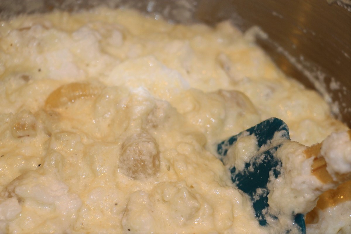 Folding stiff eggwhites into casserole, using rubber spatula. Norwegian fiskegrateng, fish casserole recipe.