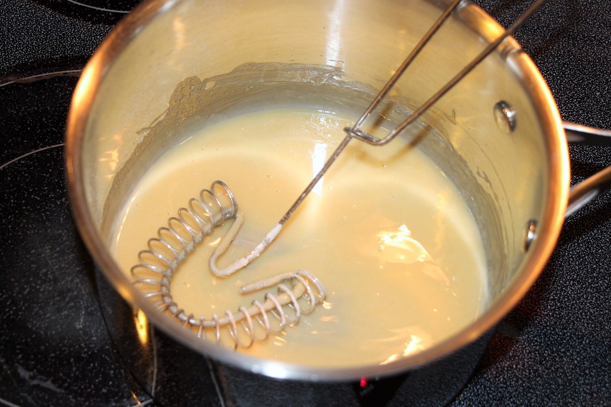 Whisking together butter and flour to make roux for white sauce.