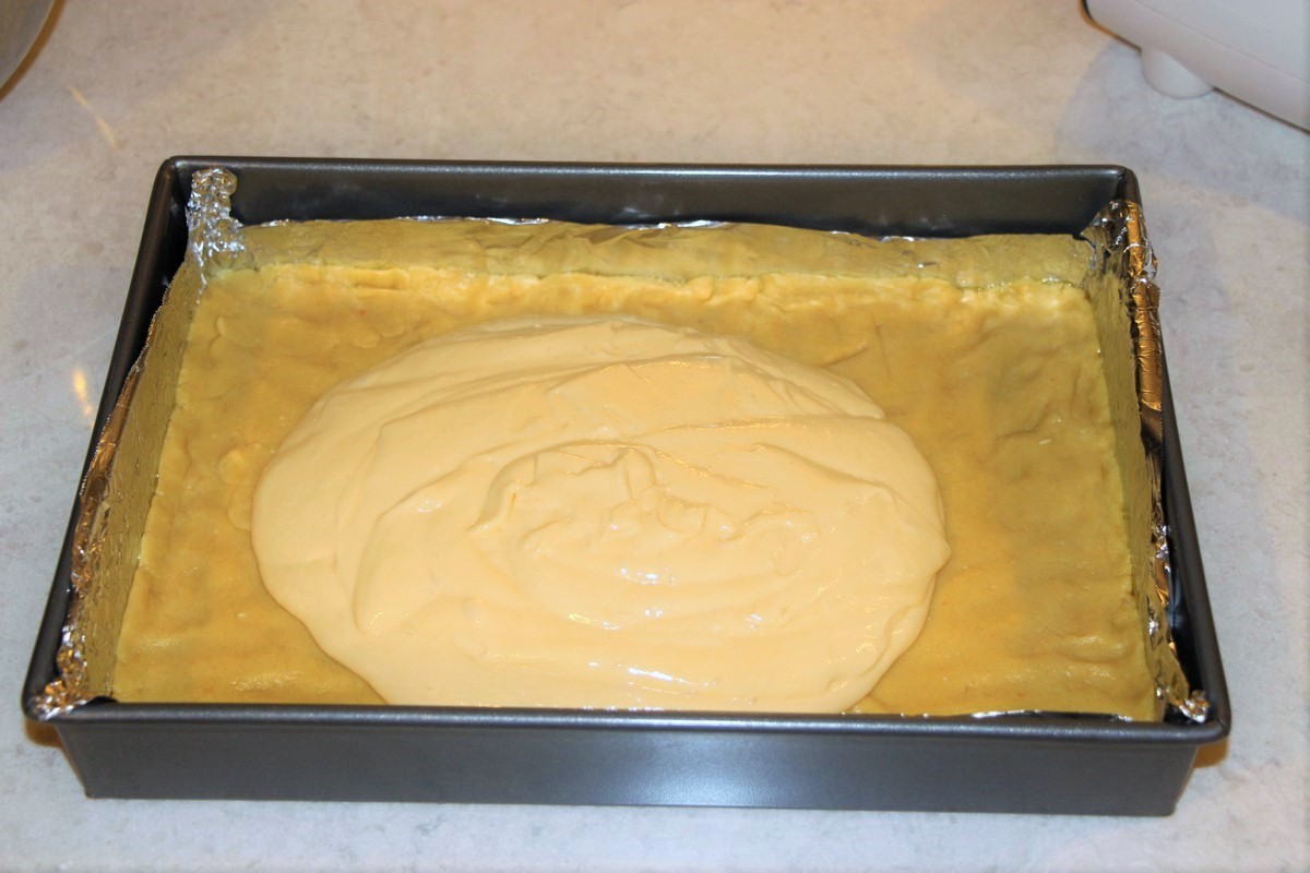 Pouring filling for cream cheese sticky bars onto cake crust. Recipe.