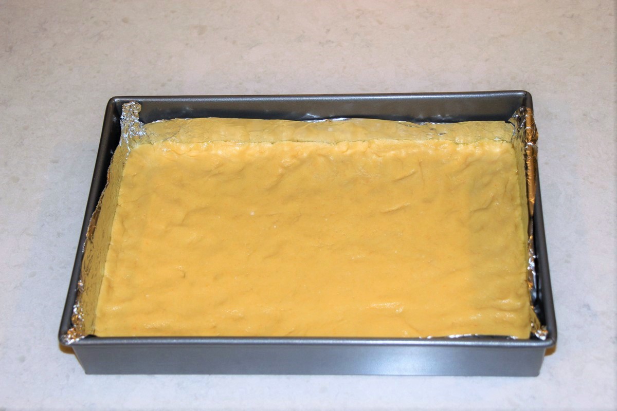 Spreadng cake dough crust into pan lined with aluminum foil, sprayed. Great tip for removing cleanly from pan.