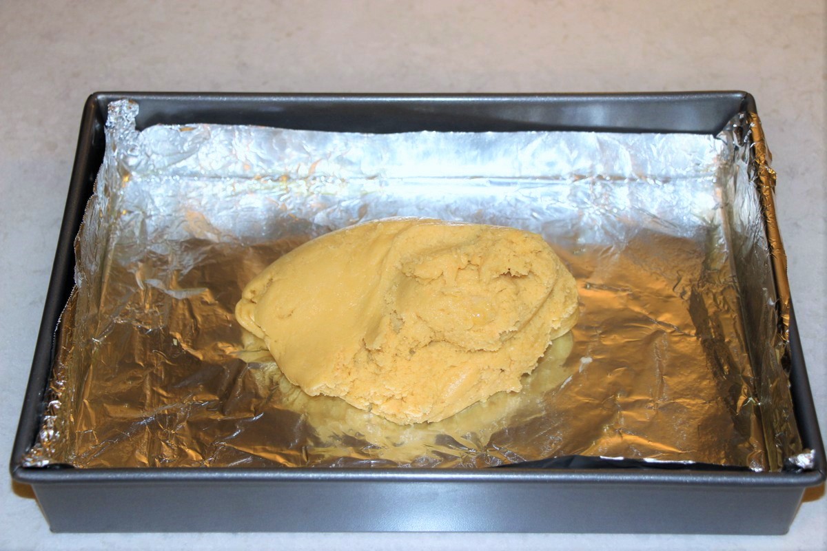 Spreadng cake dough crust into pan lined with sprayed aluminum foil. Great tip for removing cleanly from pan.