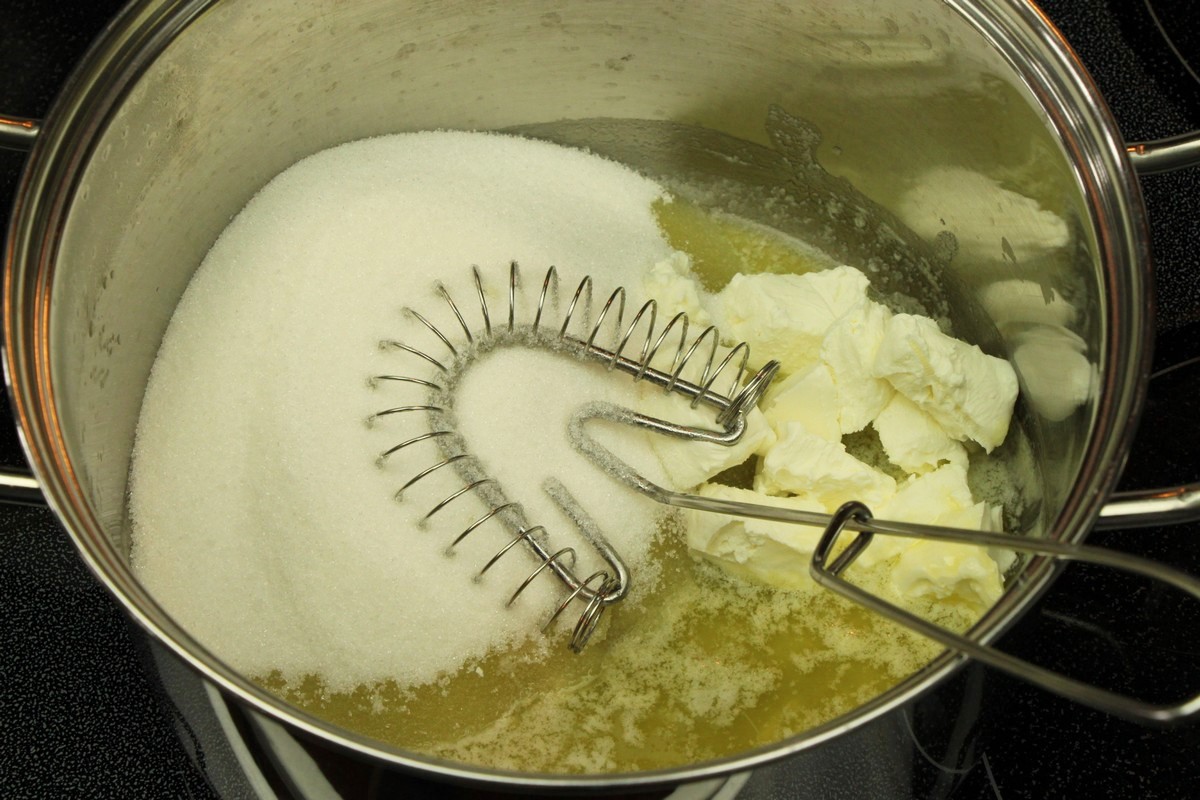 Mixing melted butter, sugar, and cream cheese for chewy sugar cookies