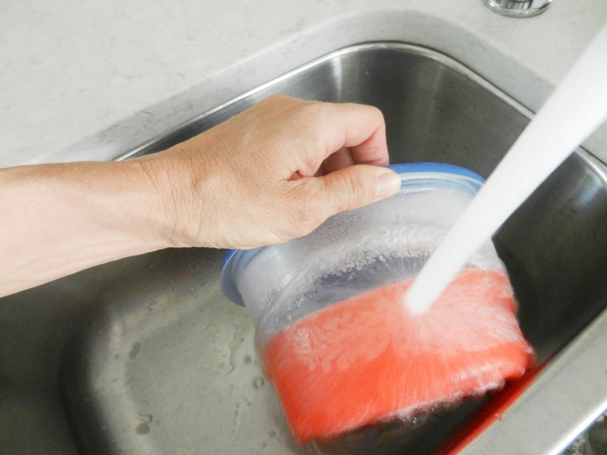 Rinsing tupperware under hot water to release frozen liquid. Pink lemonade jumbo ice cubes.